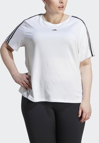 Valge sportlik t-särk mustade külgtriipudega ja väikese logoga rinnal. Lühikesed varrukad ja lõdva istuvusega, valmistatud siledast kangast.