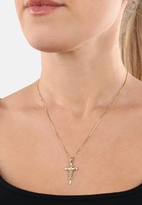 Collier en or avec un petit pendentif crucifix, présentant une texture lisse et une chaîne fine. Le pendentif affiche une image détaillée d'une figure.