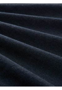 Dunkelblauem Stoff mit weicher Textur, der tiefen, fließenden Falten und subtile Farbvariationen aufweist und so ein reichhaltiges, mehrschichtiges Erscheinungsbild schafft.