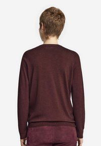 Bordeaux långärmad tröja med rund hals, ribbade muddar och fåll; mjuk textur; figursydd design, synliga sömnadsdetaljer.