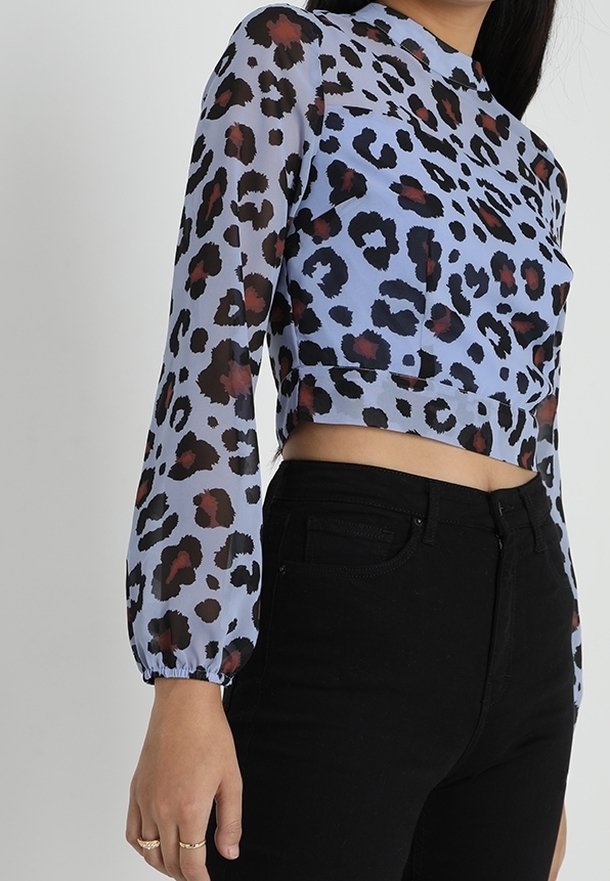 Top croppato a maniche lunghe in tessuto trasparente con base azzurro chiaro e audace stampa leopardo nera e bordeaux; presenta un collo rotondo.