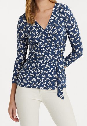 Marineblauwe wikkeltop met witte bloemenprint, lange mouwen, een diepe V-hals en een zijstrikdetail, gemaakt van een zachte, lichtgewicht stof.