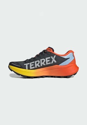 Chaussure de course Terrex noire avec grand logo latéral, semelle dégradée orange et jaune, accent bleu clair au talon, et fermeture à lacets, vue de côté.