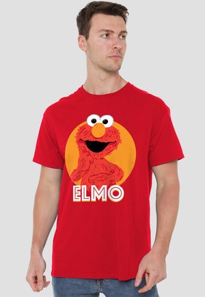 Red cotton t-shirt featuring a large graphic of Elmo with white text stating "ELMO" below it, set against a circular orange background.