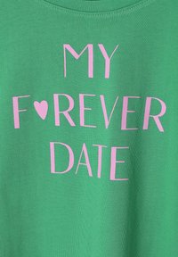 Camiseta de algodón verde con un atrevido texto en rosa que dice "MI CITA F❤️REVER." Cuello redondo clásico, textura suave, diseño casual.