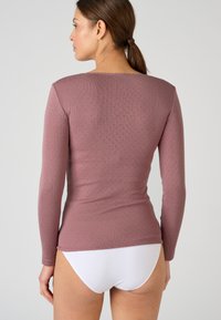 Long-sleeve top in mauve with textured pattern. Round neckline and fitted design, paired with white underwear. Smooth, stretchy fabric.