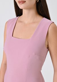 Ärmelloses Kleid aus hellrosa Stoff mit quadratischem Ausschnitt, das eine glatte Textur und subtile Abnäher für eine schmeichelhafte Passform aufweist.
