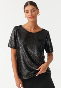 Top corto maniche corte neri con paillettes, con scollatura rotonda, caratterizzato da una texture morbida e lucida e un dettaglio di design attorcigliato in vita.