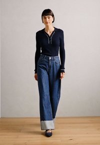 Maglione a maniche lunghe a costine blu navale con colletto, abbinato a jeans dritti in denim blu a vita alta con orlo azzurro.