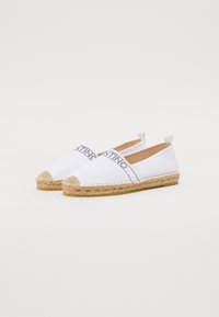 Valkoiset kankaiset espadrillot, joissa on juuttikappa ja punottu pohja, logonauhalla ylhäällä ja vetolangoilla kantapäässä.