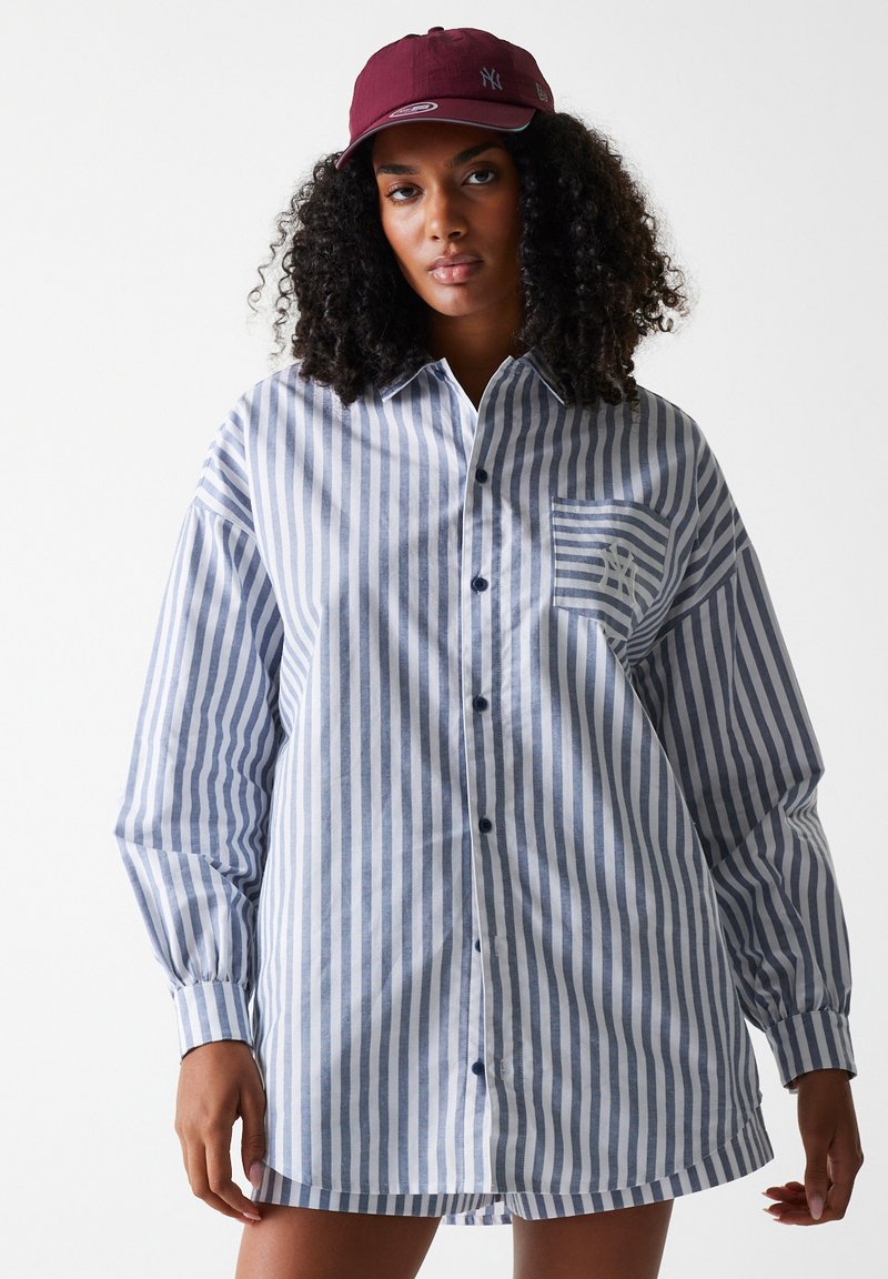 Striped button-up shirt in blue and white. Features a pocket with a logo, long sleeves, and a relaxed fit. Cotton fabric with a smooth texture.