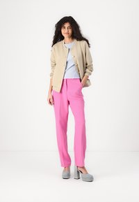 Beige texturerad jacka, ljusblå ribbad topp, klara rosa skräddarsydda byxor och grå högklackade skor. Enkla och moderna designelement.