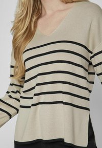 Pullover a maglia beige con strisce orizzontali nere, scollatura a V, maniche lunghe e vestibilità ampia. Texture morbida e stile casual.