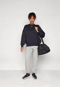 Tumesinine kapuutsiga pusa lahtise istuvusega, hallid dressipüksid, mustad tossud ja must spordikott. Textuurse kangaga ja rinnal logoga detail.