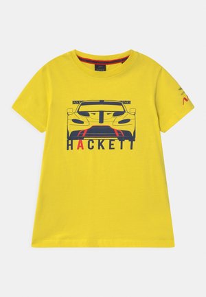 Gelbes T-Shirt mit kurzen Ärmeln, vorne ein Grafikdruck eines Rennwagens und dem Schriftzug "HACKETT", sowie einem kleinen Logo auf dem linken Ärmel.