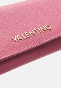 Ružasti teksturirani novčanik s zlatnim logotipom "VALENTINO", koji se odlikuje glatkom površinom i pravokutnim oblikom. Ističu se elegantne šavove i detalji.