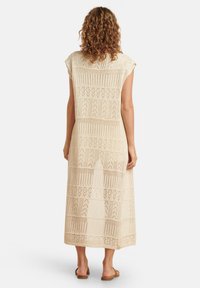 Knee-lange jurk in licht beige, met ingewikkelde open gebreide patronen en korte mouwen, met een relaxte silhouet en rechte zoom.