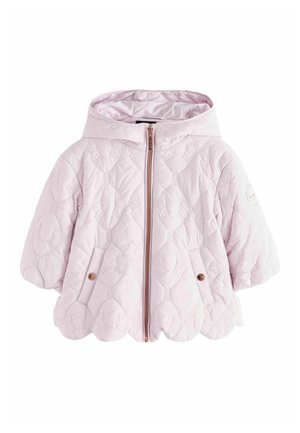 Junges Mädchen steht, trägt eine hellviolette gesteppte Kapuzenjacke, schwarze Blumenhose und weiße Schuhe mit Klettverschluss.