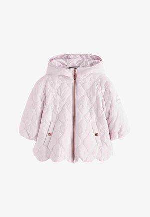 Junges Mädchen steht, trägt eine hellviolette gesteppte Kapuzenjacke, schwarze Blumenhose und weiße Schuhe mit Klettverschluss.