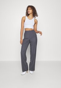 Szare spodni typu high waist o prostym kroju. W połączeniu z białym, krótkim topem na ramiączkach i białymi butami na słupku.
