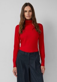 Czerwony golf z prążkowanej tkaniny, dopasowany fason. Połączony z granatowymi spodniami w pionowe paski o szerokiej nogawce, z zapięciem na guzik.