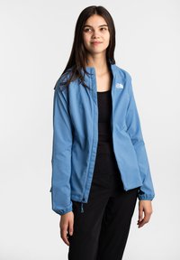 Hellblaues Outdoor-Jacke mit Reißverschluss, elastischen Bündchen und Kordelzugsaum. Das Logo von The North Face ist auf der linken Brust sichtbar.