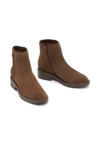Par de botas de ante marrón hasta el tobillo con cremalleras laterales y tacones bajos y gruesos, mostradas sobre fondo blanco.