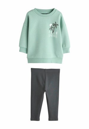 Light green sweatshirt with "Palm Springs" graphic and palm trees, paired with dark gray leggings. Both are made of soft, stretchy fabric.