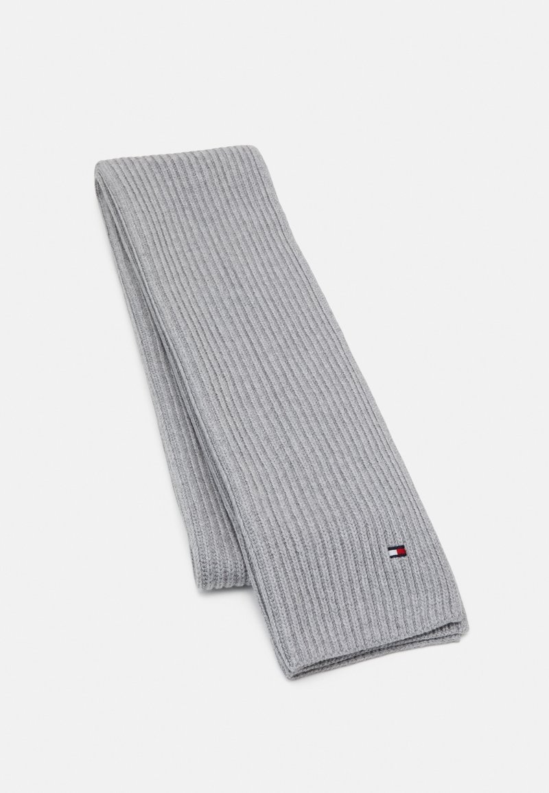 Écharpe en maille côtelée gris clair pliée avec un petit logo rectangulaire rouge, blanc et bleu près d'une extrémité sur fond blanc.