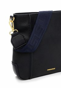 Czarna torebka ze skóry ziarnistej z odpinanym granatowym paskiem w deseń, wyposażona w złote okucia i fakturowaną powierzchnię.