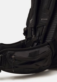 Czarna plecak z siateczkowym panelem tylnym, wyściełanymi paskami oraz kieszenią z zamkiem błyskawicznym z przodu. Wykonany z trwałego materiału z regulowanym wyposażeniem.