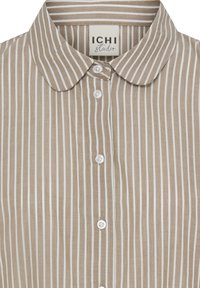 Beige og hvid stribet skjorte med knapper og rund krave, med ICHI Studio label indeni kraven.