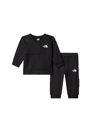 Črni dvodelni komplet z dolgimi rokavi, ki vključuje pulover z našitkom logotipa na prsih in ujemajoče se hlače z elastičnim pasom. Gladek tekstura tkanine.