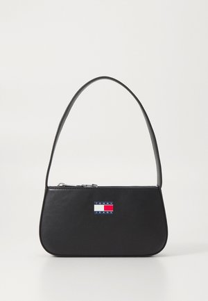Sac à épaule en cuir noir avec une sangle courte et un patch logo Tommy Jeans à l’avant, avec une fermeture éclair sur le dessus.