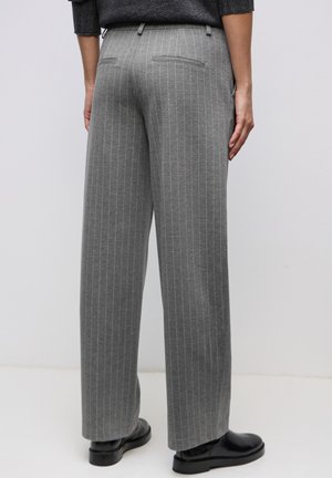 Grau gestreifte Hose mit weitem Bein, ausgestattet mit Gesäßtaschen und glatter Textur, kombiniert mit schwarzen Schuhen.