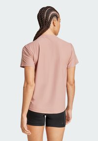 Korte mouwen, roze sportshirt met een gestructureerde stof en een subtiele glans. Heeft een ronde halslijn en een nette zoom.