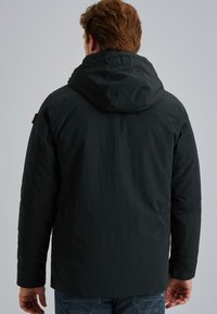 Zwarte hoodie met een gestructureerde stof en lange mouwen, met een logo op de schouder en een ontspannen pasvorm.