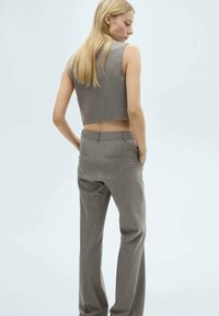 Grijze cropped mouwloze top gecombineerd met hooggepareerde grijze broeken, beide in een gladde textuur met een aangesloten fit en subtiele details.