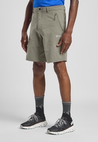 Shorts en kaki pour homme, fabriqués en tissu léger et durable, dotés de poches zippées et d'une taille ajustée pour le confort. Accentuation avec un logo.