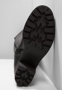 Podeszwa czarnego buta z głębokim zygzakowatym i prostokątnym wzorem bieżnika, rozmiar 37, z brandingiem "Anna Field" w części pięty.