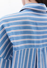 Camicia a righe blu con un motivo a spina di pesce, caratterizzata da strisce bianche e rosse. Design con colletto e dettagli sulle cuciture delle spalle.