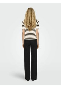 Stribet t-shirt med korte ærmer i creme og sort, parret med brede sorte bukser. Toppen har vandrette striber og en klassisk pasform.