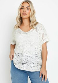 Top blanco de punto con mangas cortas, diseño calado y un ajuste relajado. Presenta un escote redondeado y un efecto ligeramente degradado en el dobladillo.