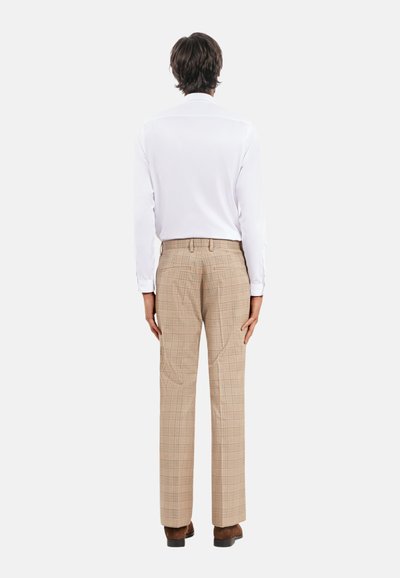 Chemise blanche légère à manches longues associée à un pantalon à carreaux beige. Le pantalon présente un motif à petits carreaux et une coupe droite.