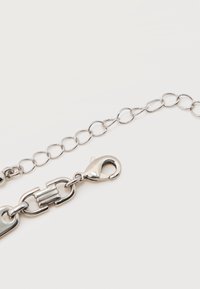 Αλυσίδα από ασημί μέταλλο με κούμπωμα καβουράκι και ρυθμιζόμενους οβάλ κρίκους σε απλό λευκό φόντο.