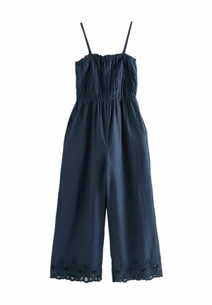 Combinaison bleu marine sans manches avec bretelles fines ajustables, corsage froncé, jambes larges, poches latérales et détails d'ourlet en dentelle festonnée.