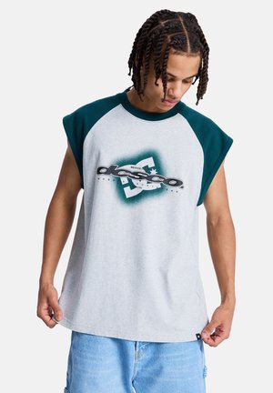 Szara, oversize'owa koszulka z zielonymi rękawami raglanowymi. Z przodu znajduje się graficzne logo w czerni i bieli, podkreślające nowoczesny design. Miękka tekstura.