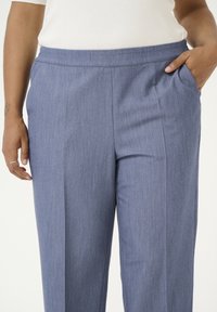 Siniset räätälöidyt housut, joissa on teksturoitu pinta, suora leikkaus, sivutaskut ja keskipitkä vyötärönauha.