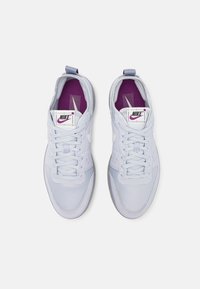 Ljusblåa träningsskor med ovandel i mesh, platta snören och en lila innersula. Har en vit swoosh-logotyp och perforerade detaljer.