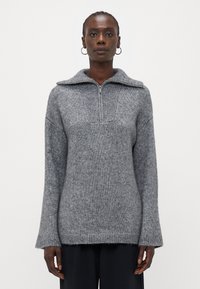 Maglione grigio a maglia con colletto a mezza zip, dettagli a coste sul petto e maniche ampie. Morbido al tatto e con una vestibilità comoda.